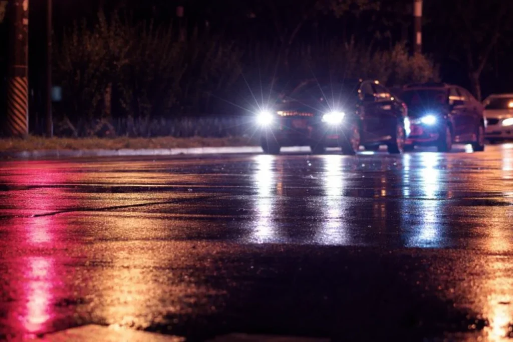 Well-lit pickup point at night with a black sedan arriving and clear visibility