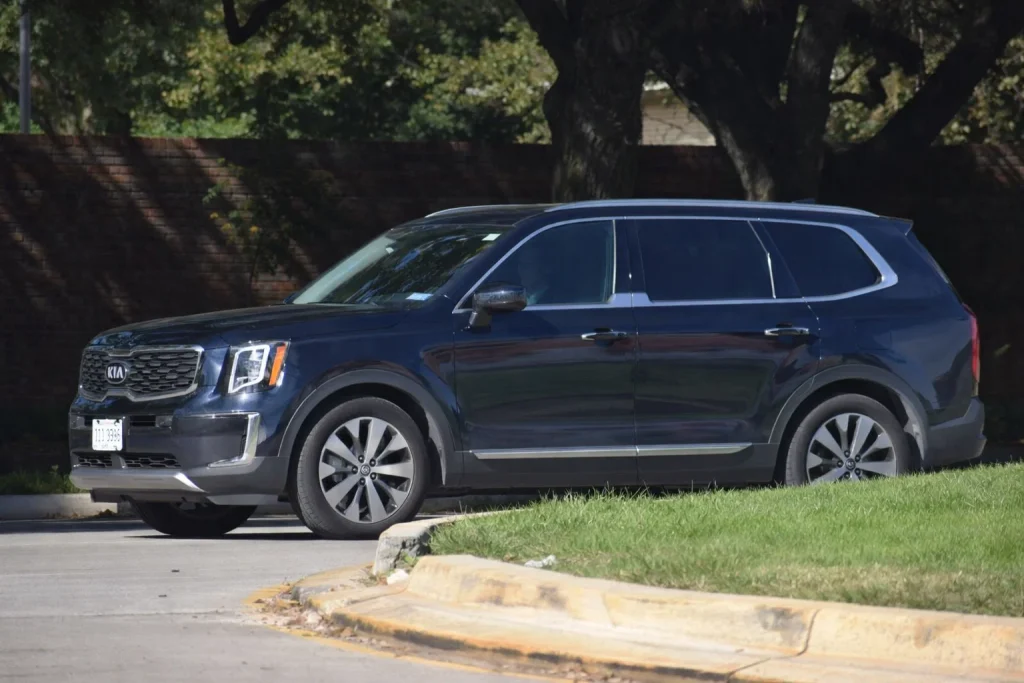 Black SUV waiting in a safe pull-off lane while a busy curb is visible in the distance