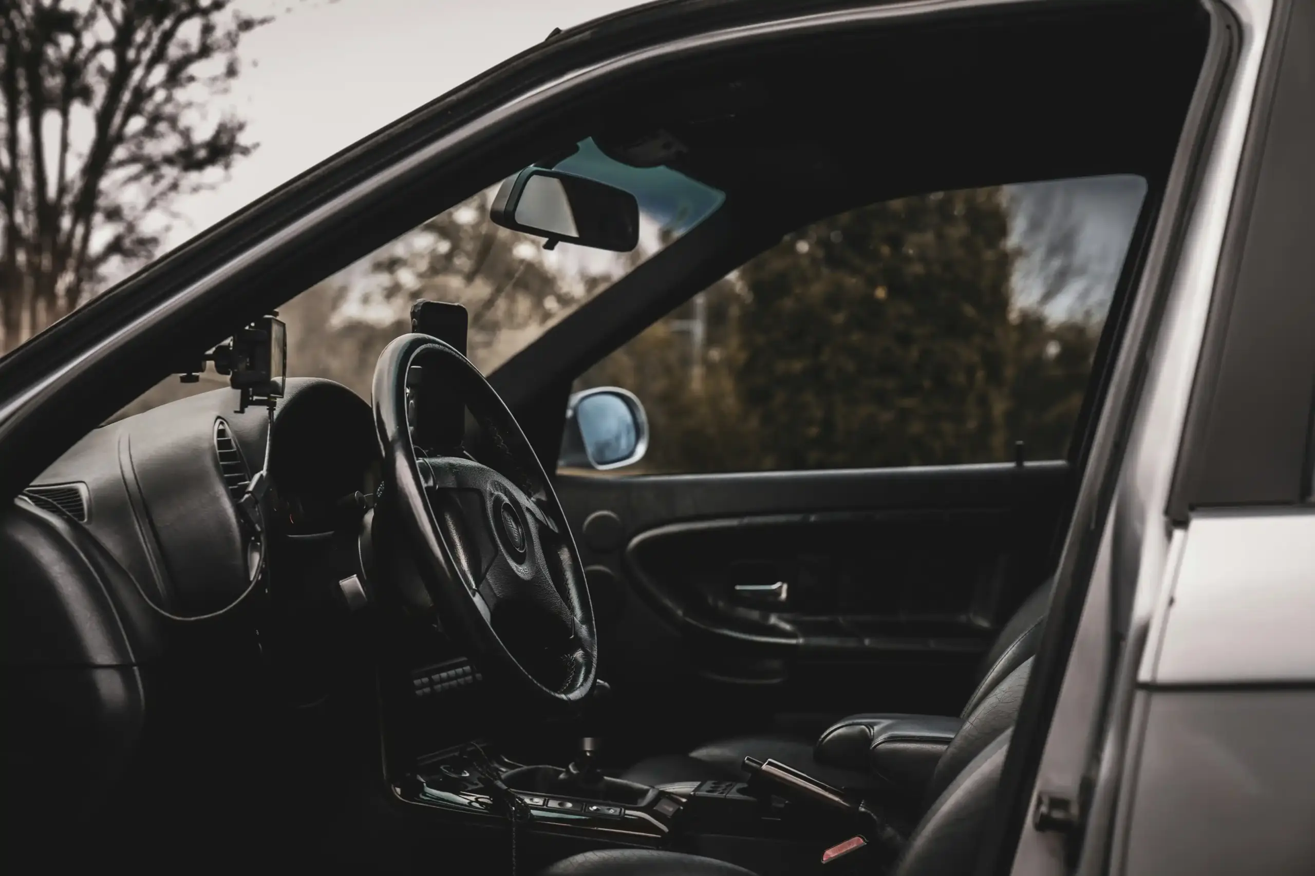 split-screen style scene showing price comparison on laptop beside luxury airport car interior with leather seats, bottled water, and city skyline through window
