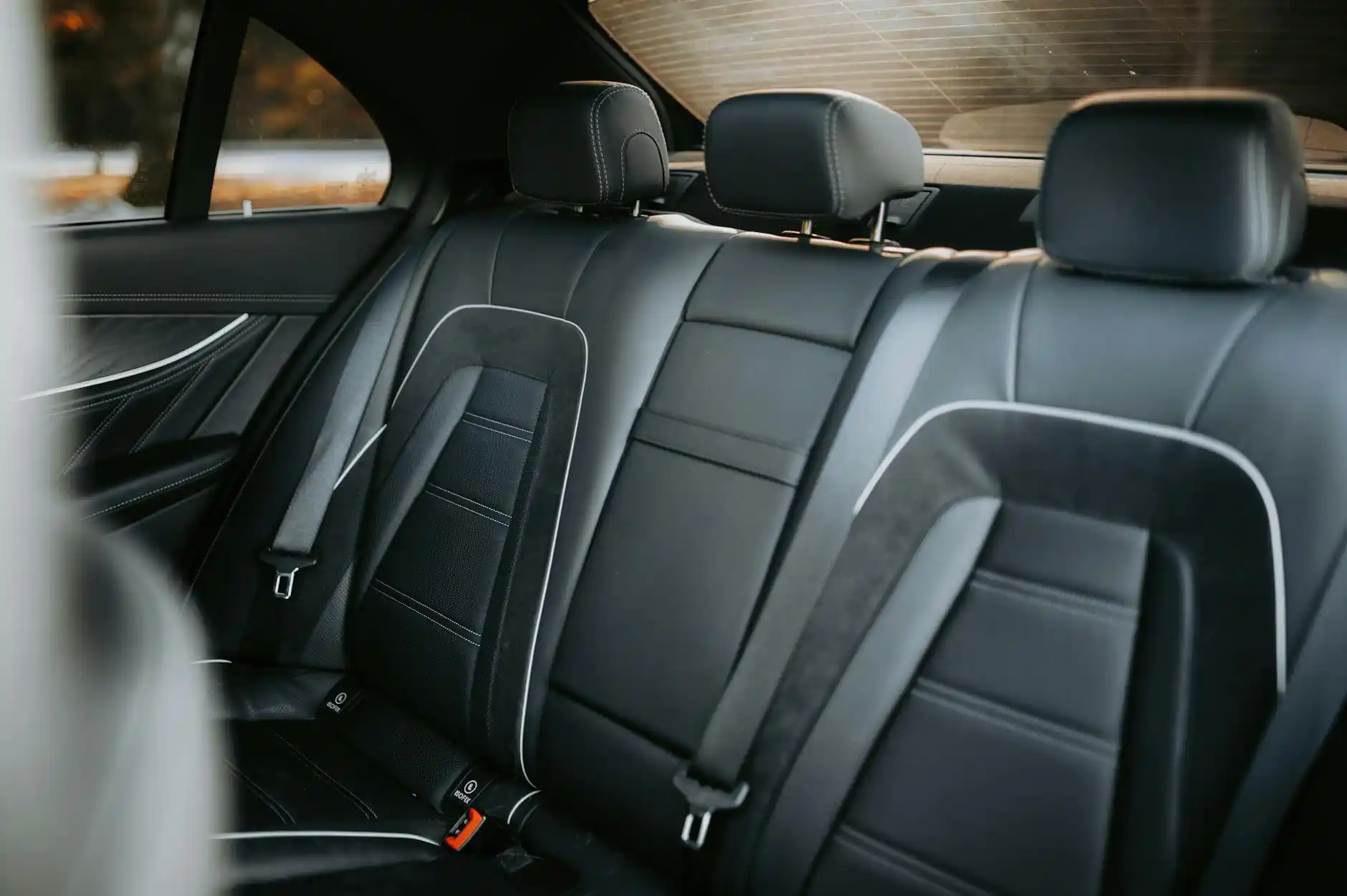 executive traveler seated comfortably in a premium black town car, laptop bag beside them, Seattle skyline in the distance through the window, soft interior lighting and leather...