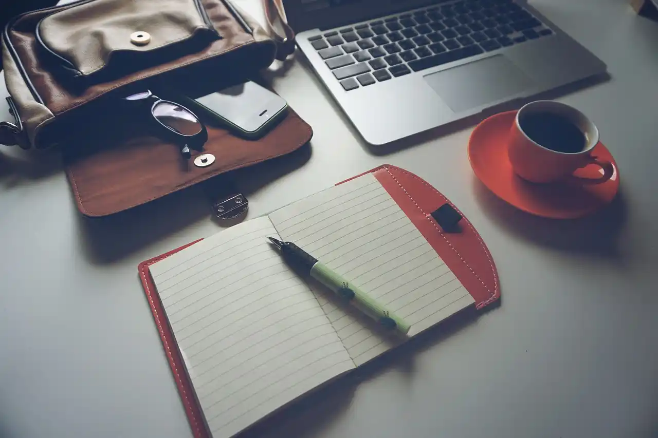 executive assistant at a desk in a modern Bellevue office booking black car transportation on laptop, skyline visible through window, coffee, calendar, and smartphone on desk