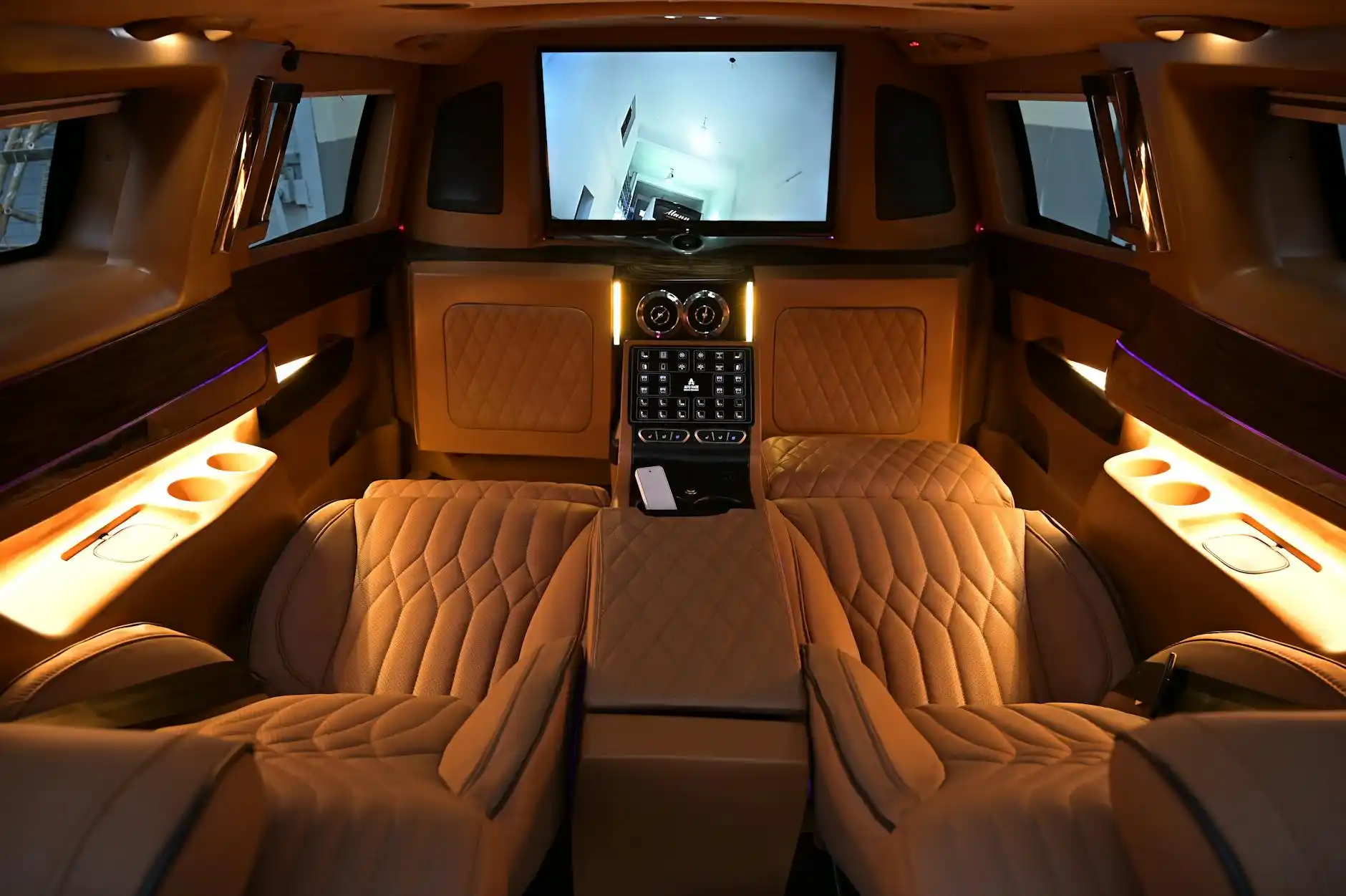 interior of an executive limousine with tan leather seats, soft ambient lighting, business traveler reviewing itinerary on tablet, carry-on luggage neatly stored beside the seat