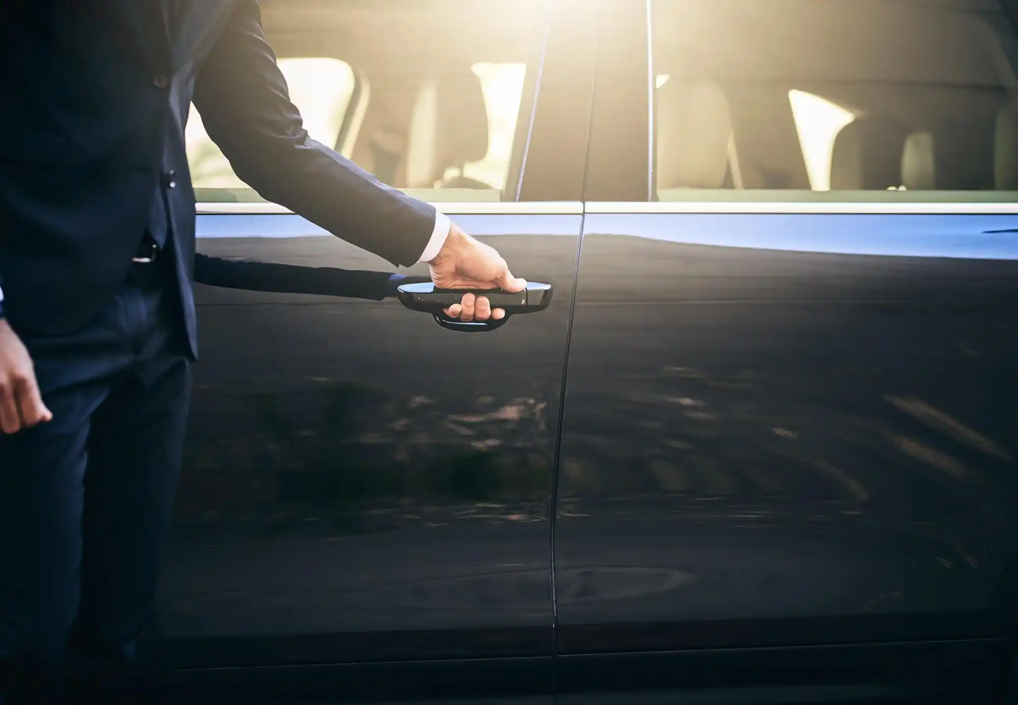 black luxury sedan arriving at a modern glass office tower in downtown Bellevue during morning business rush, chauffeur opening rear door, executives with briefcases, clean Paci...
