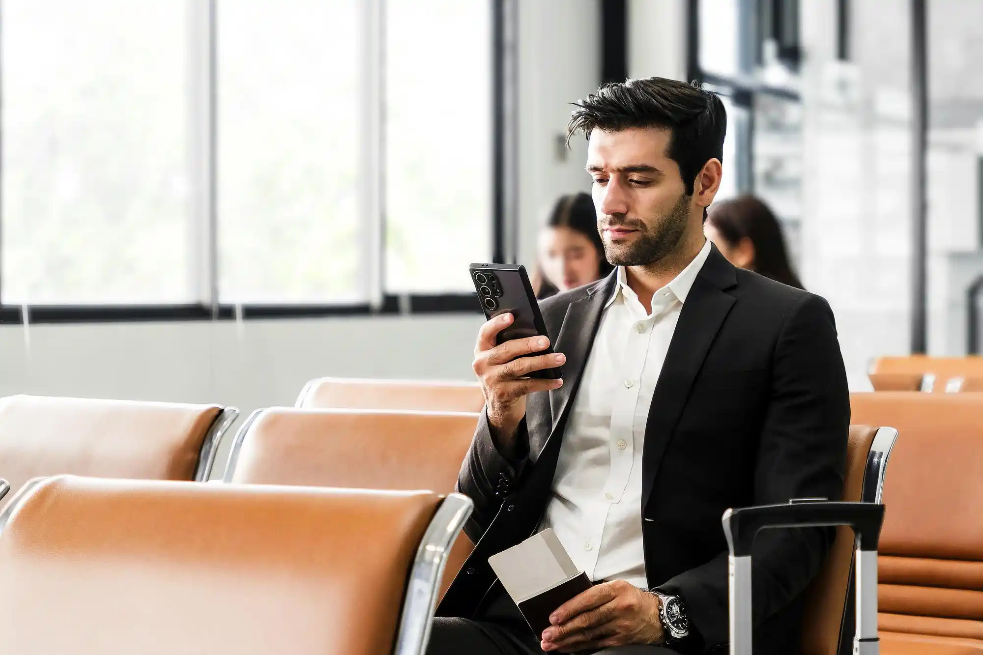 upscale hotel entrance in Bellevue with black SUV at valet stand, business traveler checking phone, bell staff with luggage, rainy Pacific Northwest atmosphere reflected on pave...