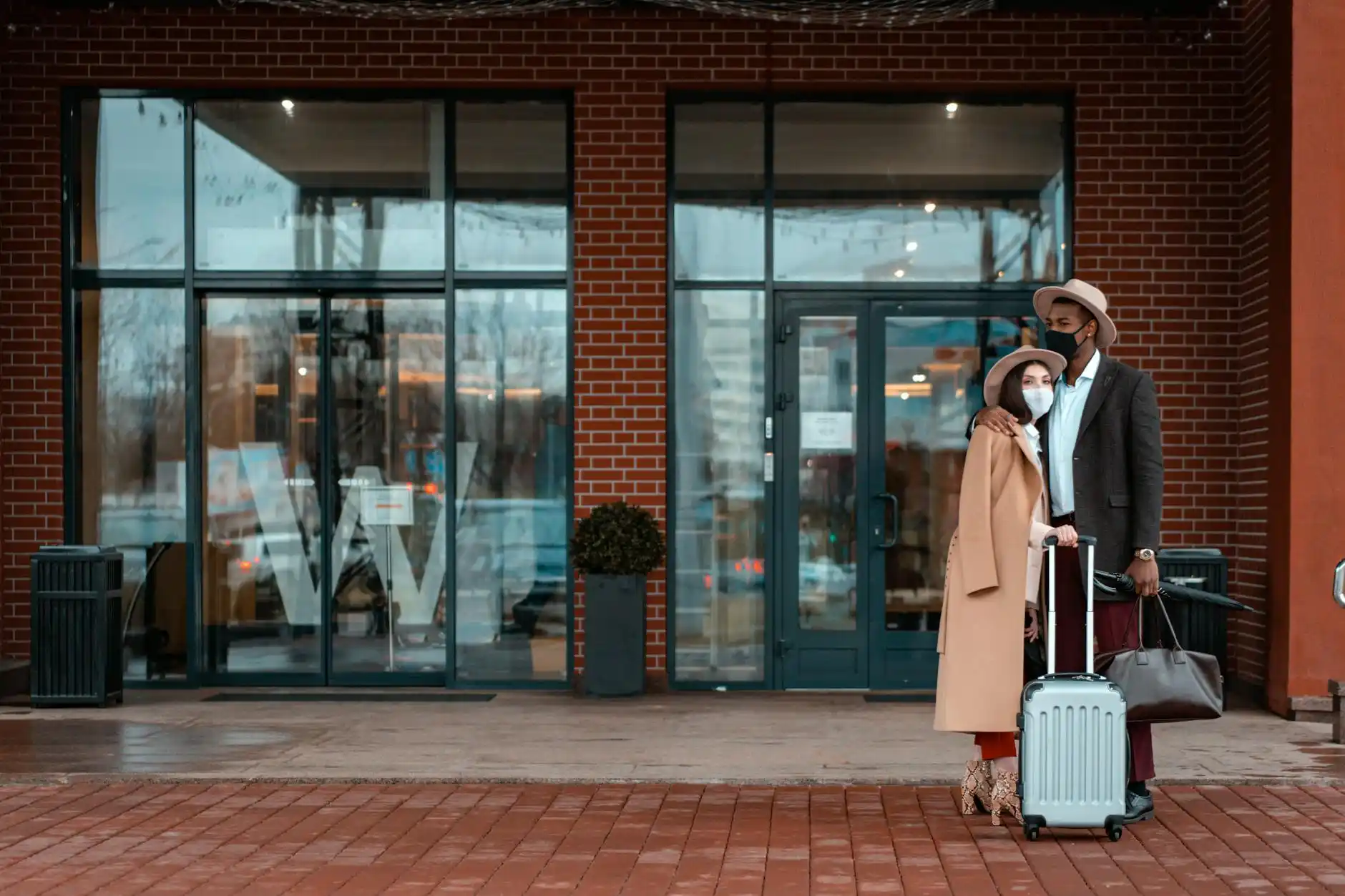 upscale Seattle hotel entrance in Belltown with concierge stand, black town car at curb, couple with suitcases and shopping bags preparing for pickup