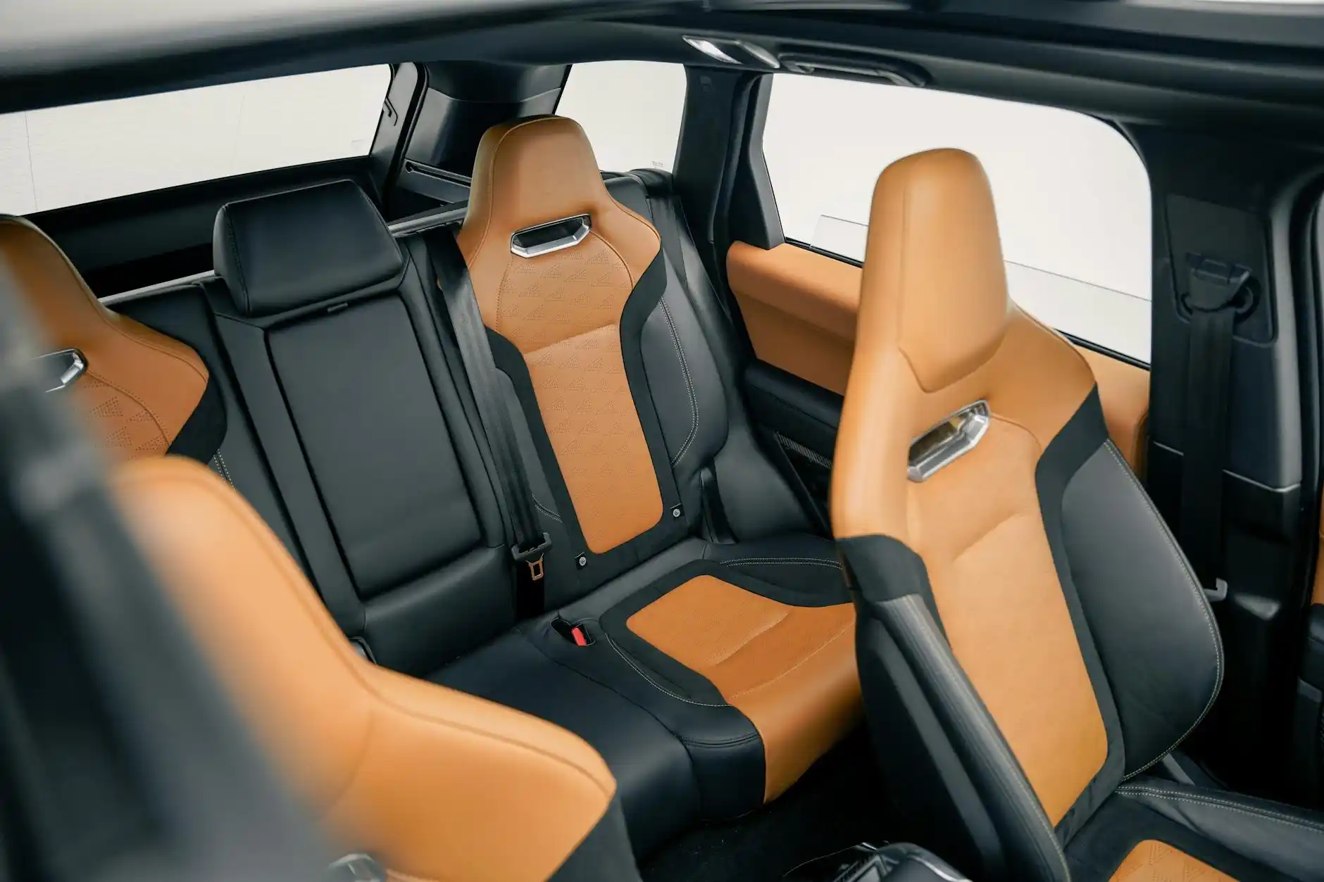 spacious black SUV interior with tan leather seats, bottled water in center console, large suitcases neatly loaded in rear cargo area, soft natural daylight through tinted windows