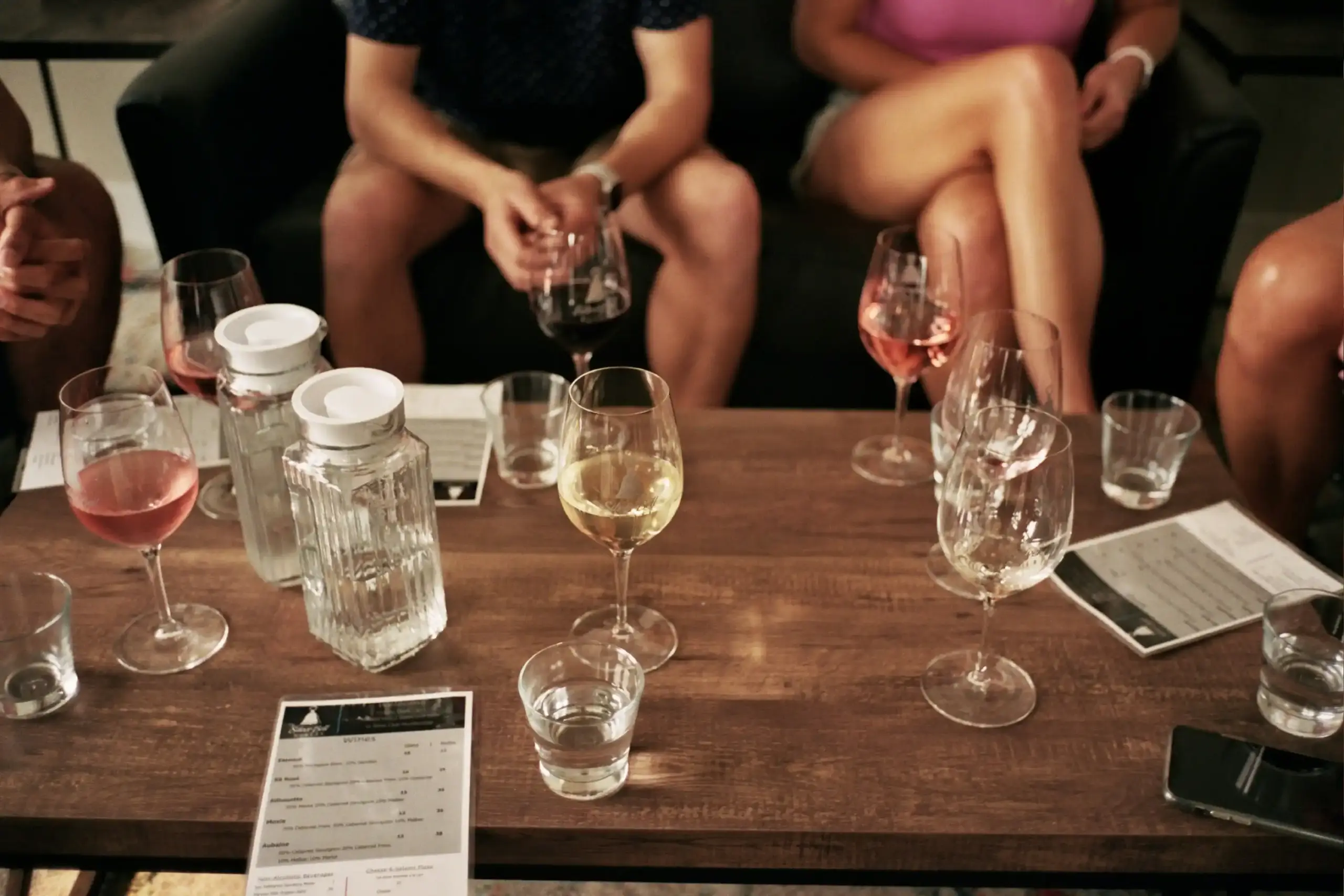 group of six friends arriving at a contemporary Woodinville tasting room, smiling as they step out of a premium sprinter van, landscaped winery entrance and overcast Pacific Nor...