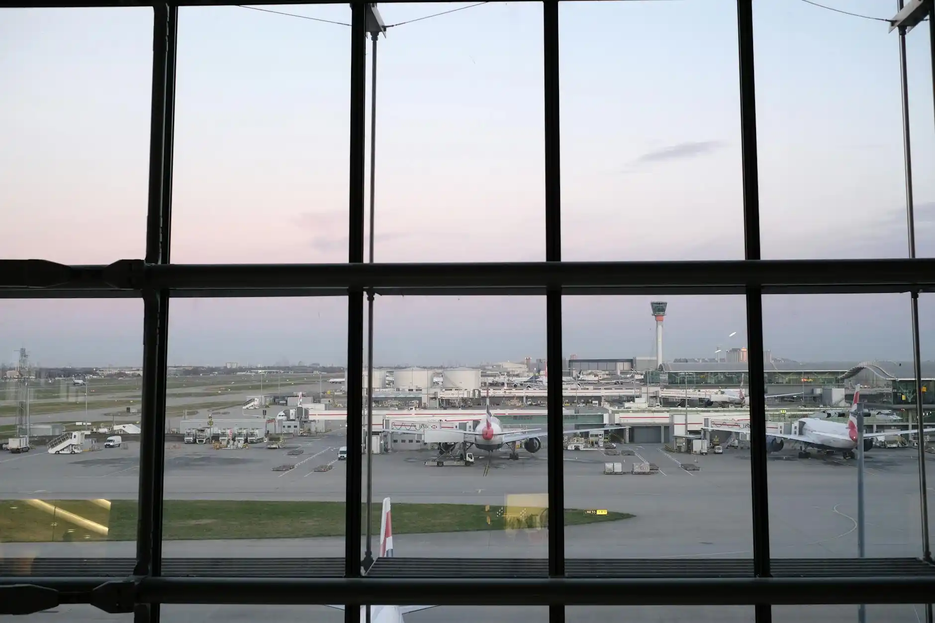 black luxury limousine parked at Seattle-Tacoma International Airport curbside during early morning light, professional chauffeur opening rear door, travelers with rolling lugga...