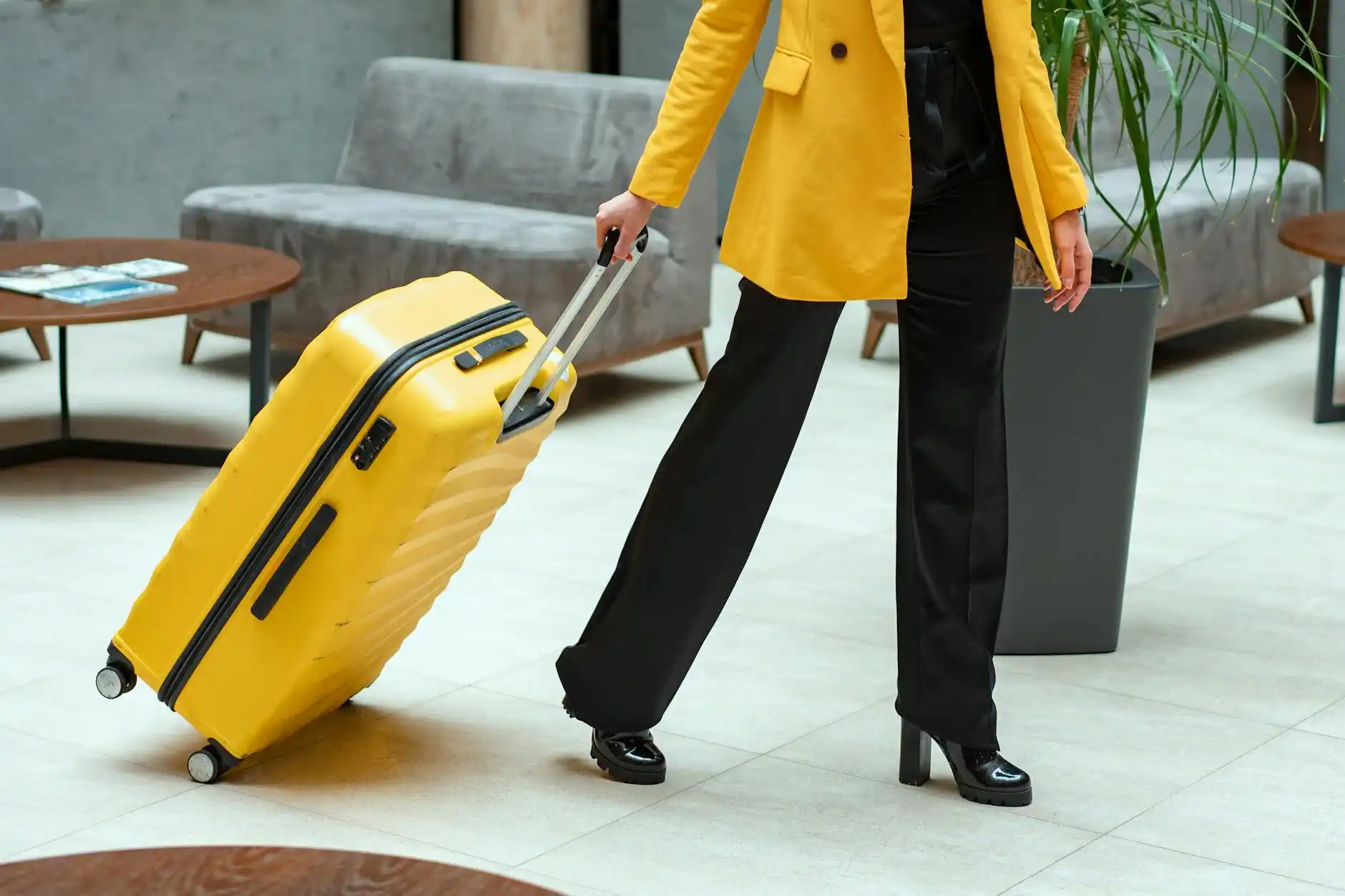 traveler in Seattle hotel lobby checking watch beside rolling suitcase while black airport shuttle waits outside under covered entrance, polished modern hotel setting