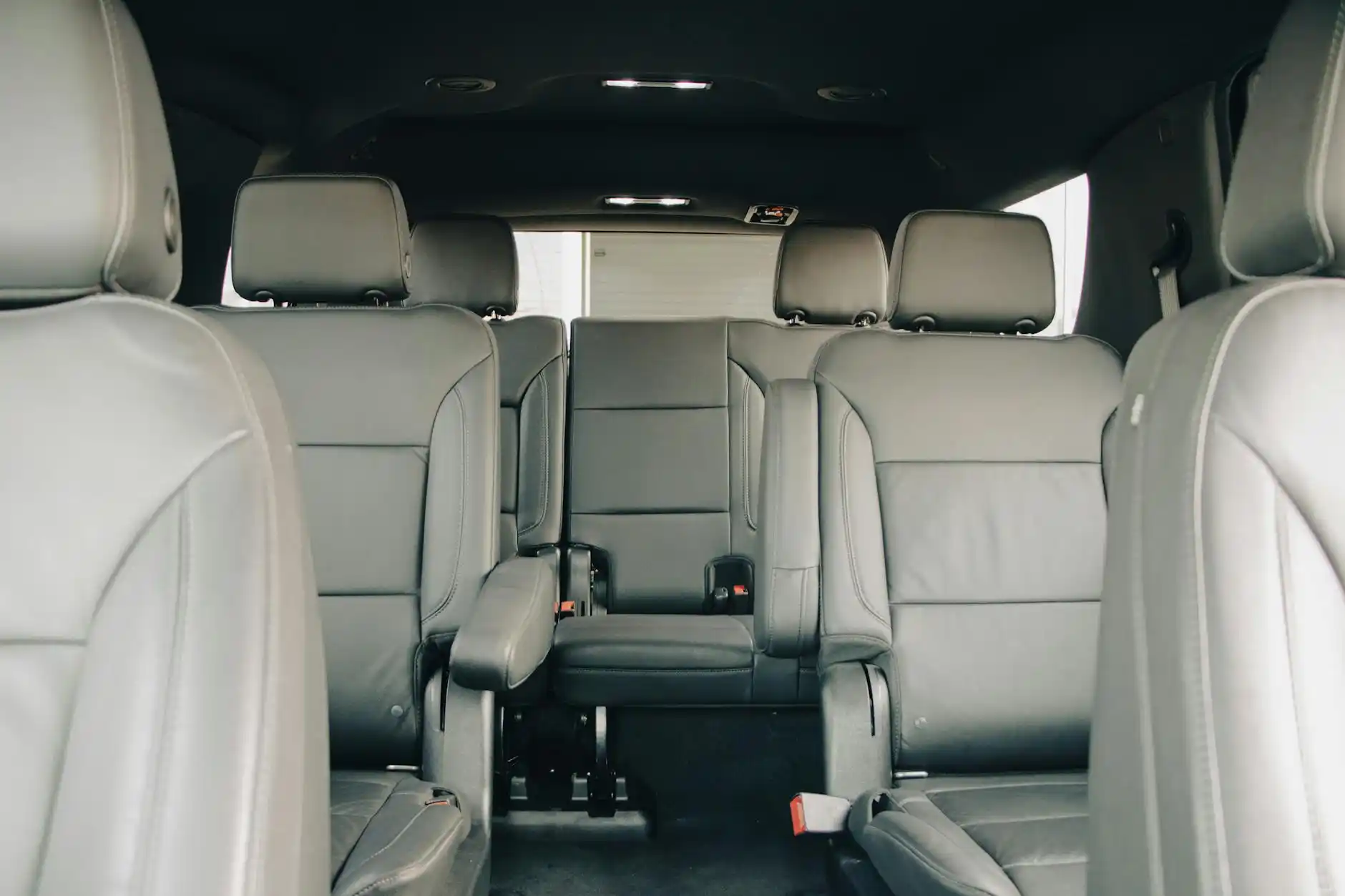 spacious luxury SUV interior with beige leather seats, carry-on bags neatly arranged, a family looking relaxed on the way to SEA airport during a gray Seattle morning