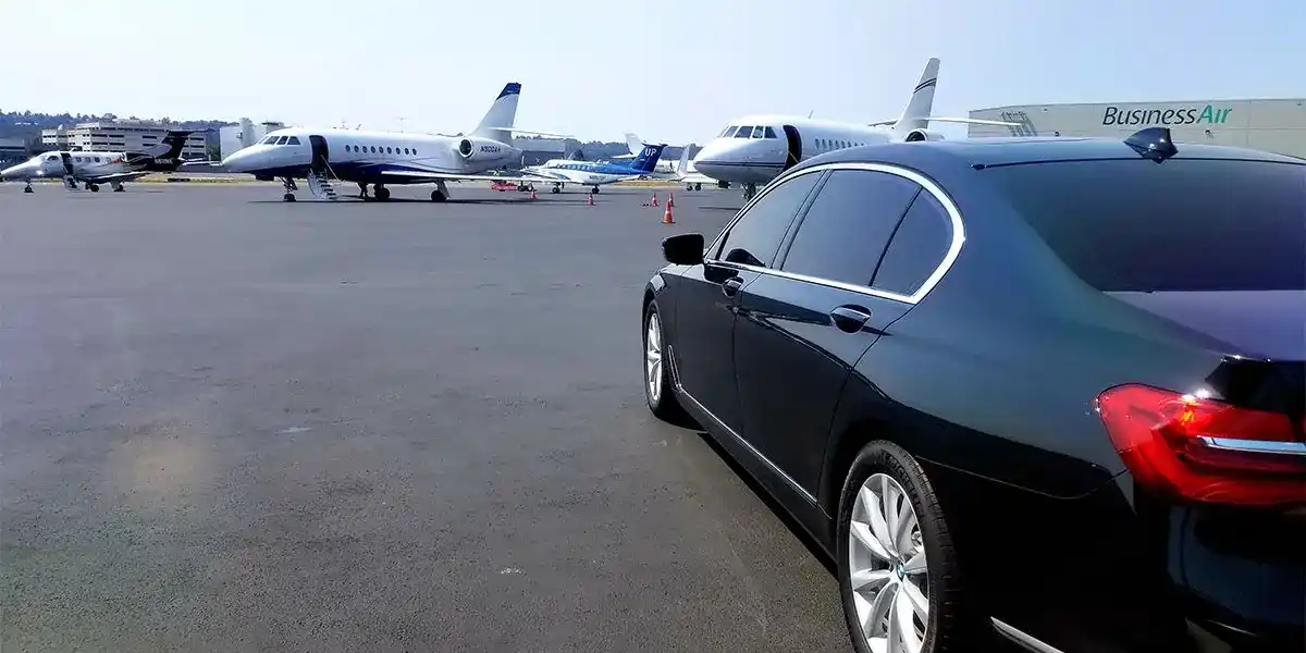 interior of a luxury black SUV with tan leather seats, bottled water, soft ambient light, laptop bag and family luggage neatly arranged, rainy Bellevue skyline through windows