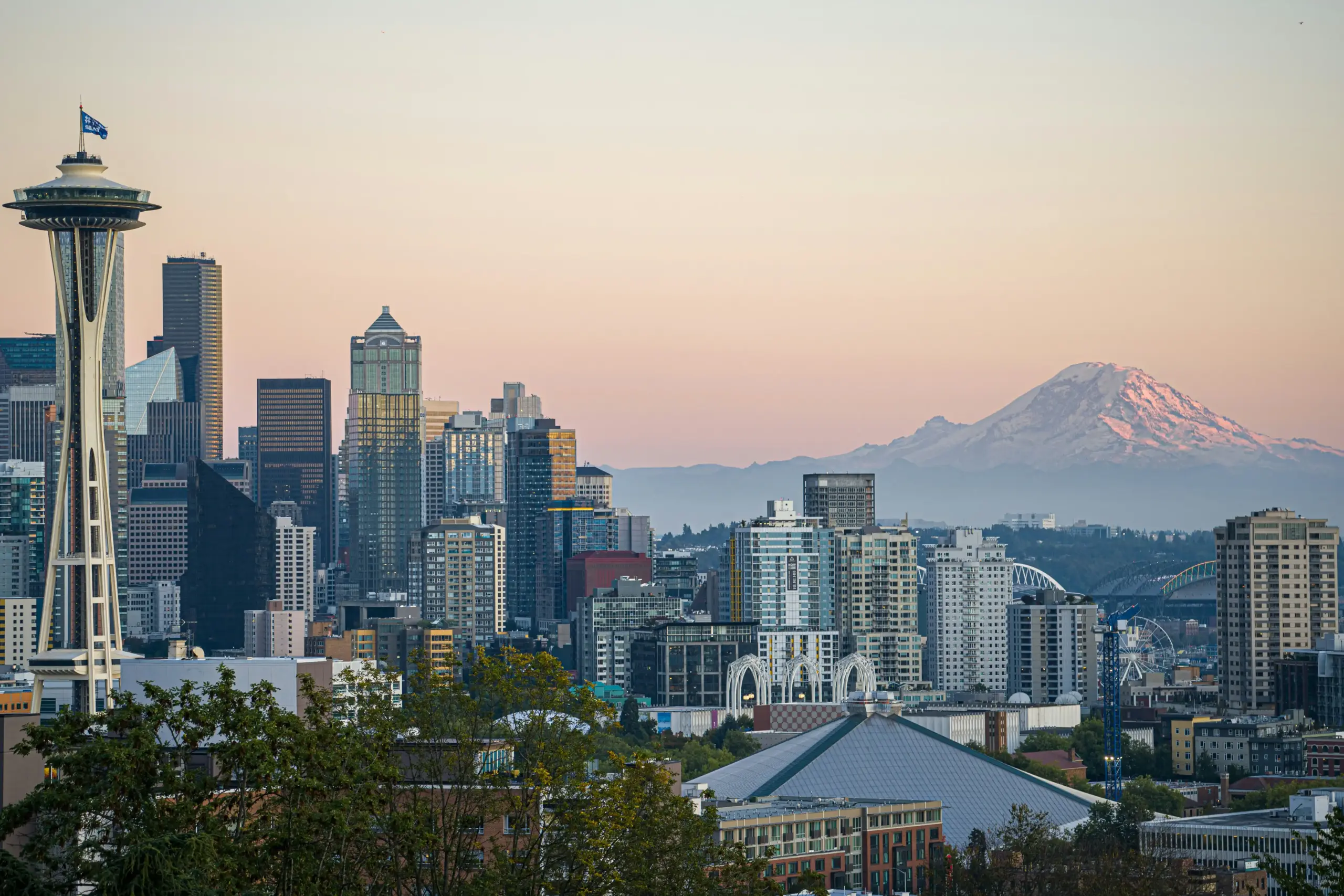 black luxury SUV parked at a modern downtown Seattle curb at sunrise, chauffeur opening the rear door, skyline and Space Needle softly visible in the background