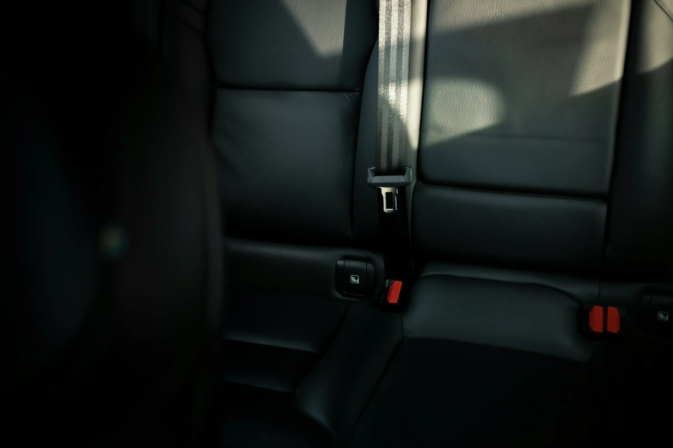 luxurious black car interior with tan leather seats, bottled water, charging ports, and large windows overlooking the scenic Pacific Northwest highway