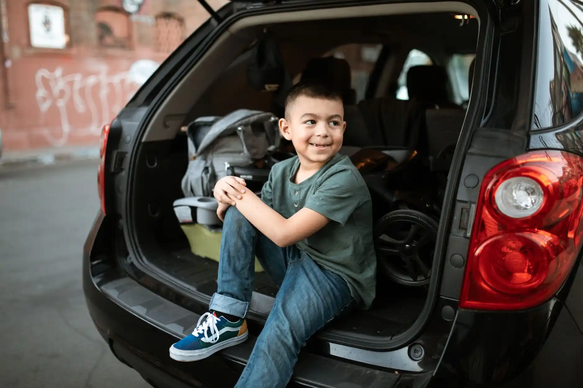 spacious luxury SUV cargo area neatly arranged with four hard-shell suitcases, two carry-ons, child seat installed, and soft natural daylight