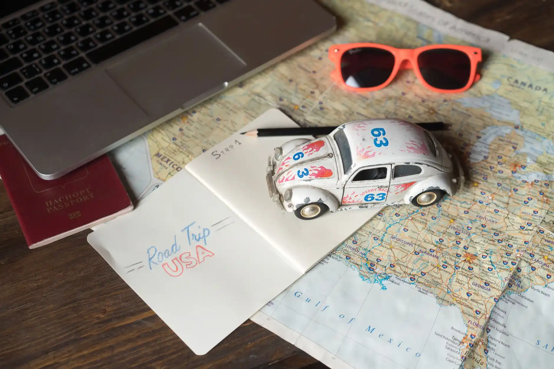 close-up of chauffeur service booking confirmation on smartphone next to passport, car keys, and printed Vancouver itinerary on a wood desk