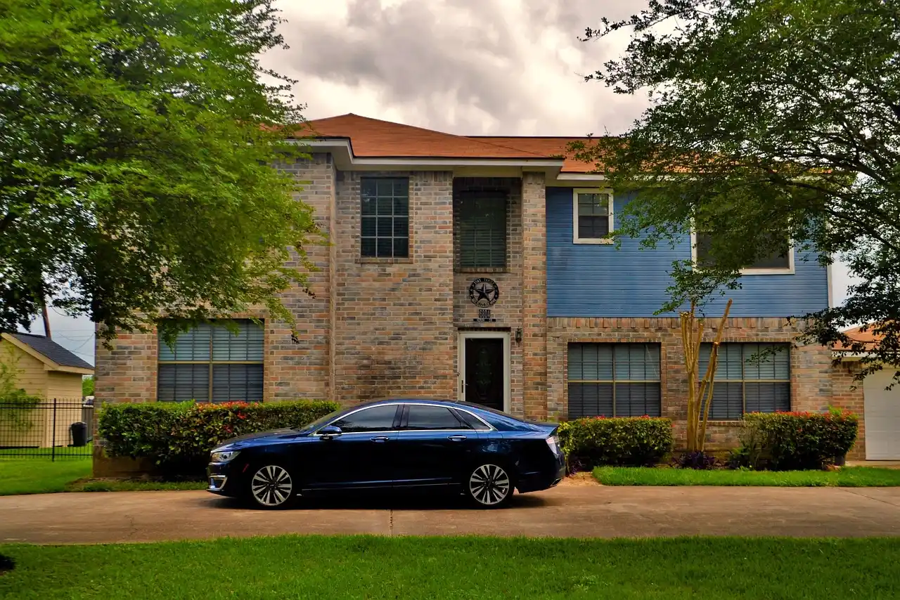 black luxury sedan parked in a quiet Sammamish residential driveway at sunrise, chauffeur opening the rear door, evergreen trees and upscale suburban homes in the background