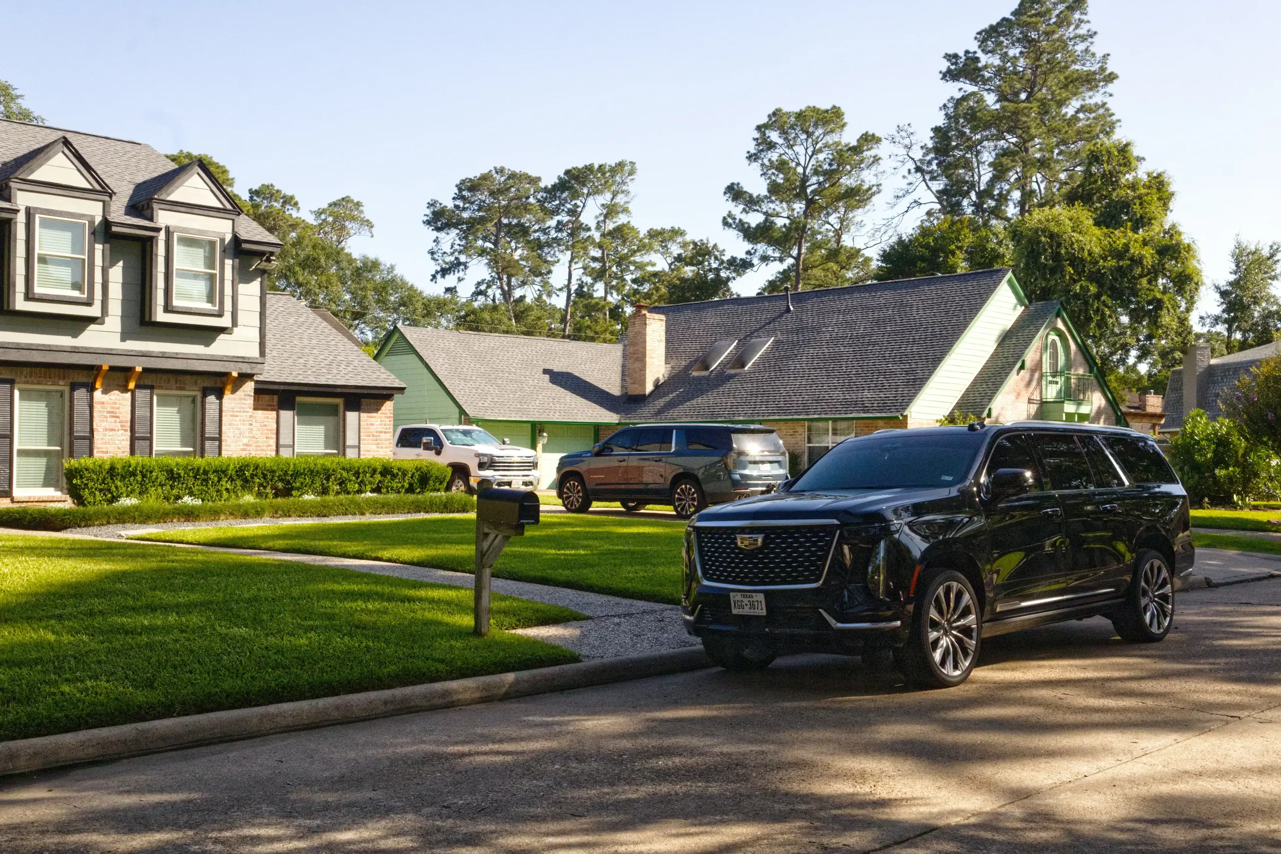 family outside a modern Sammamish home loading large suitcases and a child booster seat into a black luxury SUV before an airport trip