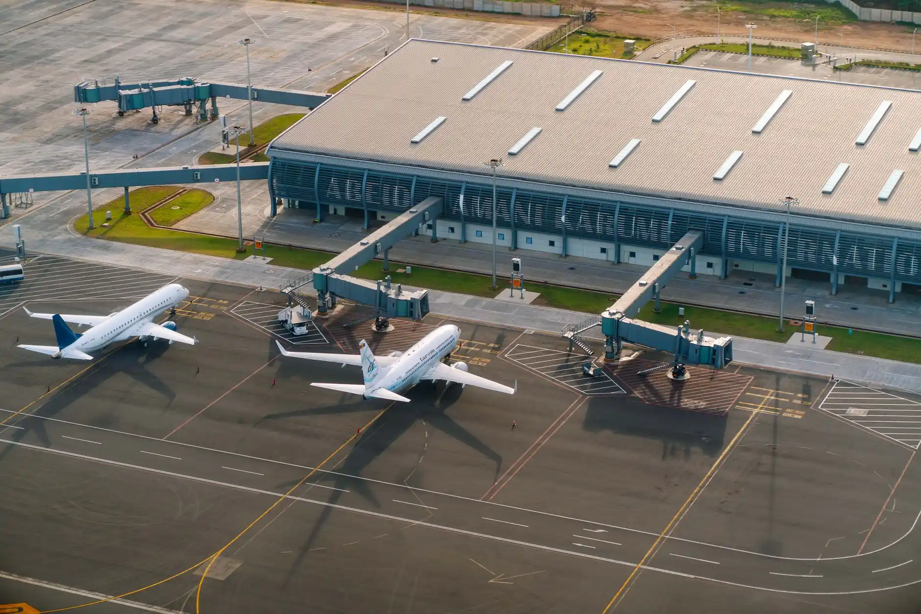 aerial-style view of SeaTac Airport terminal roadways at dusk with a black executive vehicle approaching departures, glowing runway lights in the distance