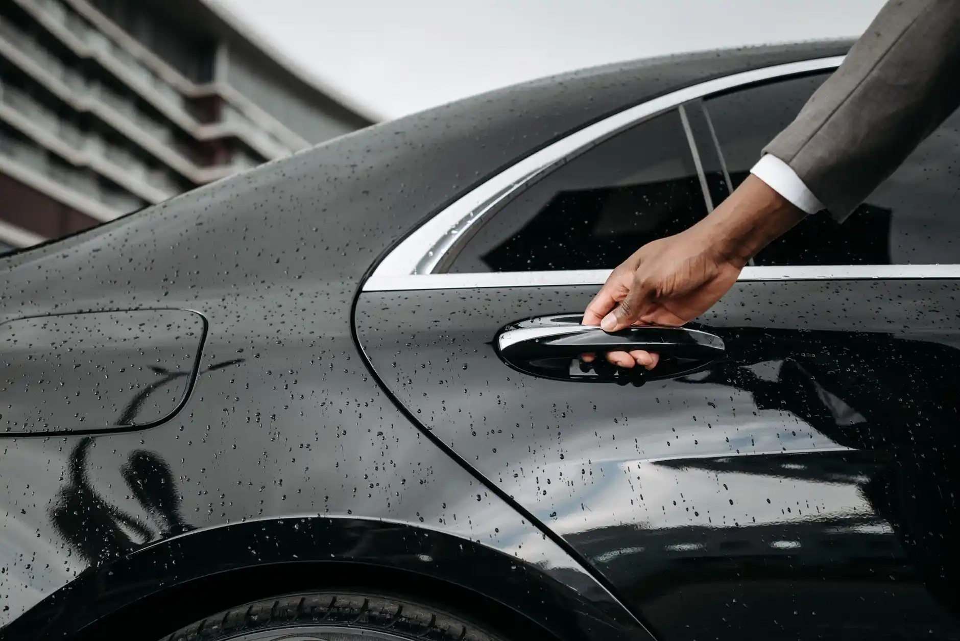 black luxury town car parked at Seattle-Tacoma International Airport curbside during golden hour, chauffeur opening the rear door, travelers with premium luggage, terminal light...