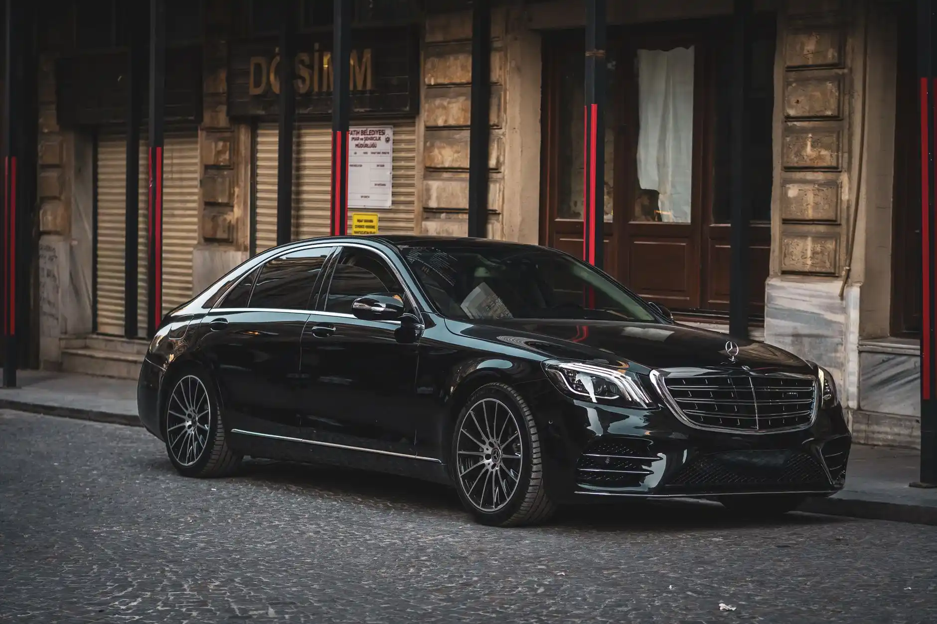 sleek black luxury sedan parked at Seattle-Tacoma International Airport curbside on a rainy evening, city lights reflecting on wet pavement, chauffeur opening rear door in forma...