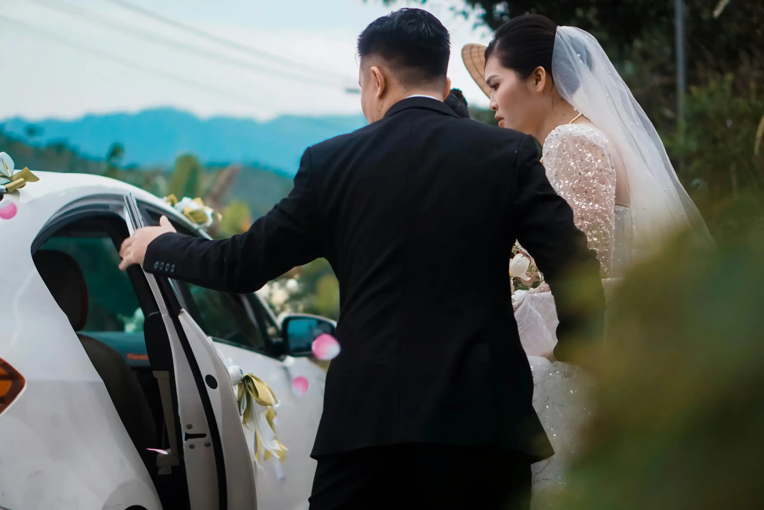 elegant bride and groom stepping into a glossy black stretch limousine outside a Seattle wedding venue with soft rain, downtown skyline, and warm evening lights