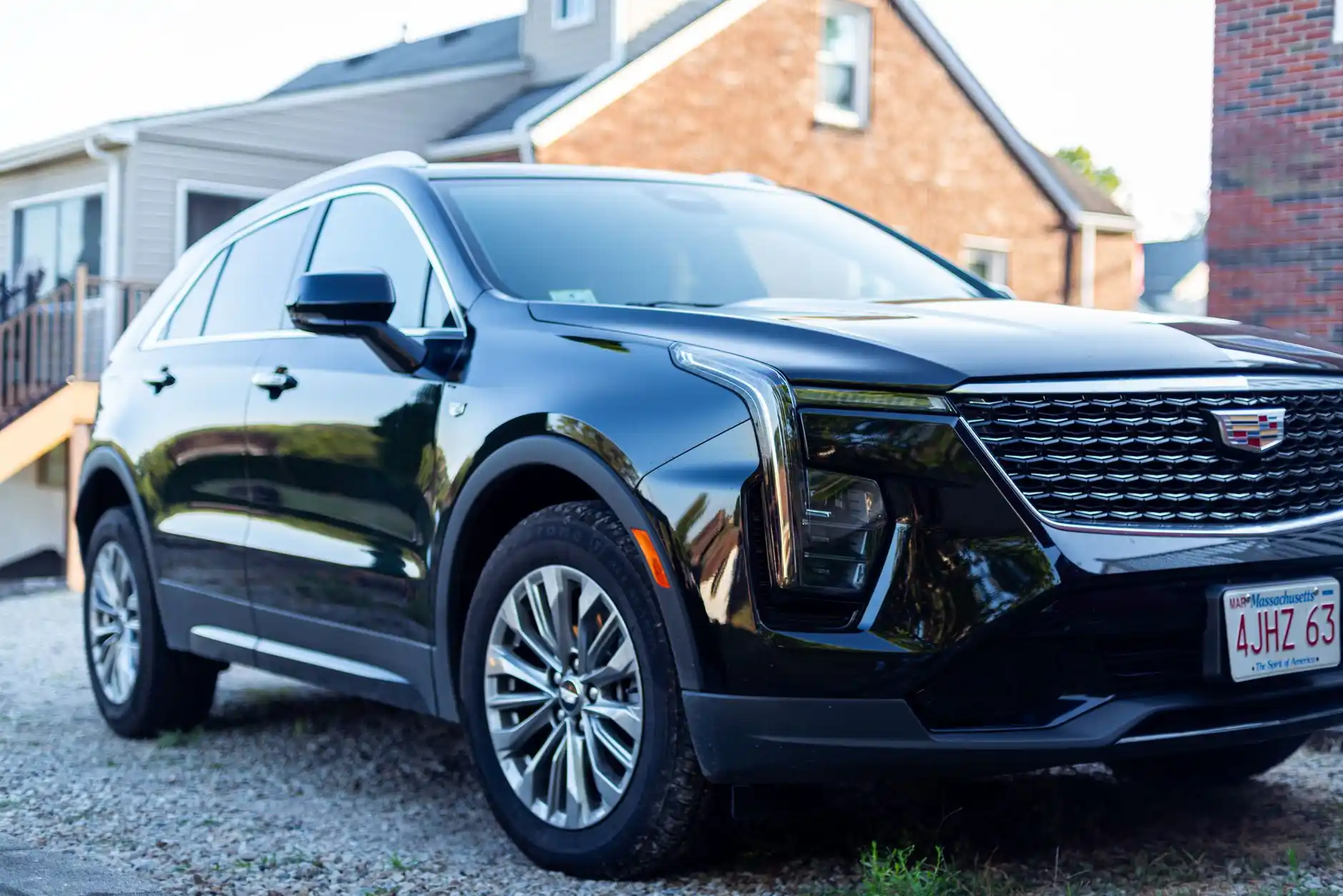 black luxury SUV parked at a mountain-view home driveway in North Bend at dawn, professional chauffeur loading airport luggage, overcast Pacific Northwest lighting