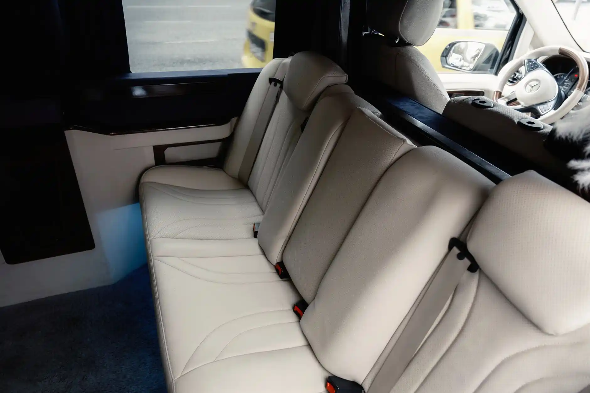 luxury sprinter van interior with 14 leather seats occupied by a mixed corporate group, laptops and phones charging, panoramic windows, overhead lighting, clean aisle, premium s...