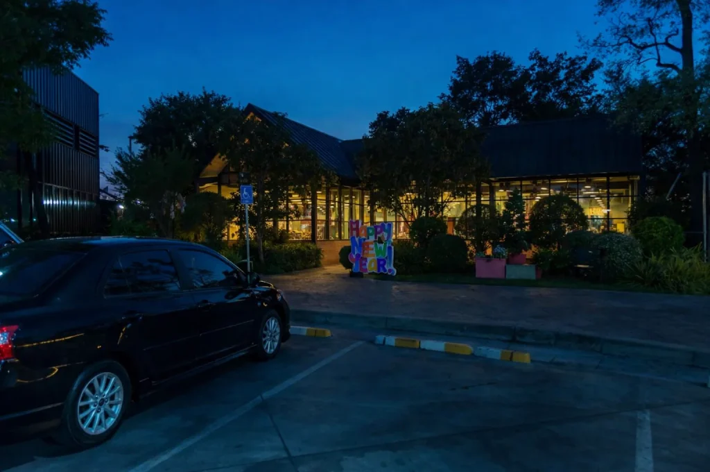 Well-lit meet point at night with vehicle arrival and passenger waiting safely with minimal wandering